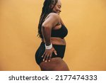 Body positivity and happiness. Smiling black woman standing against a studio background in black underwear. Mature woman with dreadlocks embracing her natural and ageing body.