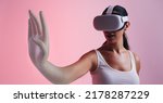Small photo of Woman transforming into a 3D avatar in the metaverse. Female gamer entering a game while wearing virtual reality goggles. Young woman experiencing immersive technology in a studio.