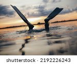 Scuba diver diving into the sea with his fins above the water. Man scuba diving at sunset.