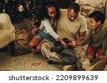 Happy military family playing with their cat at Christmas. Military dad reuniting with his children at home. Soldier spending quality time with his family after military deployment.