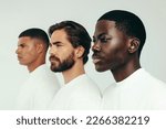 Men displaying confidence and beauty as they stand together in a studio. Three young men, each with a unique skin tone, show the flawless results of self-care and a consistent skincare routine.