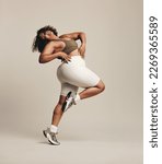 Small photo of Woman embodying self-confidence and self-assurance as she dances in sportswear. Active young female making a self-expression through an effortless body movement in a studio.