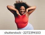 Excited woman with a fit and curvy form having a great time in a lively dance workout. She celebrates her body, proudly showing her confidence as she expresses herself through body movement.
