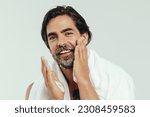 Small photo of Happy caucasian man takes pride in his grooming routine, carefully applying shaving cream to his beard. With a steady hand and a focused gaze, he prepares his face for a close shave in a studio.