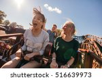 Young friends on thrilling roller coaster ride. Young women and men having fun at amusement park.