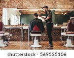 Rear view shot of handsome hairdresser cutting hair of male client. Hairstylist serving client at barber shop.
