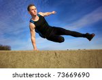 Young man jumping over wall on obstacle course