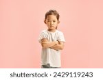 Small photo of Offended Little Asian Girl Defiantly Crossed Arms in Front of Her Expressing Dissatisfaction and Resentment Standing Over Pink Isolated. Children Capricious Disposition and Negativity Concept.