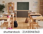 Small photo of Wide angle background image of wooden school desks in row facing blackboard in empty classroom, copy space
