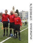 Small photo of MILAN, ITALY-MARCH 17, 2019: soccer referee with linesmen wearing red uniform, enter the pitch, during a kids soccer match, in Milan.