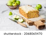 Small photo of Apple and coconut oaf cake on wooden cutting board and apples in a vase
