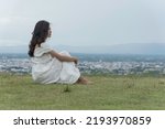 woman sit facing side on grass at top mountian look at sky  nature view. feel relax.