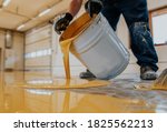 Worker applying a yellow epoxy resin bucket on floor.