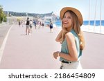 Portrait of attractive fashion woman turns around and smiling at camera walking along Promenade des Anglais, Nice, France