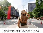 Visiting Sao Paulo City, Brazil. Rear view of beautiful tourist woman with hat walking along Paulista Avenue, Sao Paulo, Brazil.