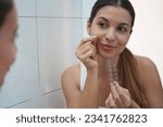 Small photo of Close-up of beautiful woman applying acne treatment anti-pickel patch on a pimple in bathroom