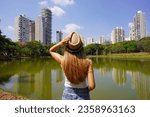 Small photo of Visiting Goiania, Brazil. Back view of young woman in Parque Sulivan Silvestre also known as Parque Vaca Brava, a city park in Goiania, Goias, Brazil.