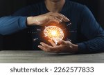 Small photo of Close up of businessman hand holding brain in palm, Virtual reality man with symbol neurons in the brain. Concept of idea and innovation, on wooden table.