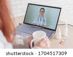 Small photo of A woman with a cold is on sick leave and is looking at a laptop video consultation frendly doctor. A patient at a remote appointment. Online meeting.