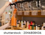Small photo of A man fills a jar with red lentils. Selling bulk goods by weight in an eco store. Trade concept without plastic packaging