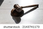 Small photo of Wooden judicial gavel on a wooden laminate.