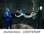 Small photo of A man teaches a woman how to fly in a wind tunnel. Free fall simulator.