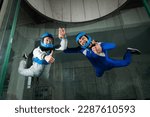 Small photo of A man and a woman enjoy a joint flight in a wind tunnel and give a thumbs up. Free fall simulator.
