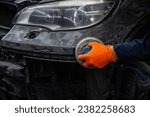 Small photo of A mechanic sands the putty on a car body with a machine. Repair after an accident.