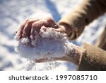 Small photo of Women's hands in winter without gloves make a snowball and make a heart out of it