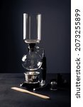 Small photo of Vacuum coffee maker also known as vac pot, siphon or syphon coffee maker on rustic black stone table.
