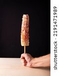 Small photo of Mexican Street corn cob is a popular street snack in Mexico, it is tender corn cooked with spices, skewered on a wooden stick covered with mayonnaise or sour cream, fresh cheese and piquin chili powd