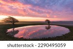 Vibrant dawn sky reflecting in the Ditchling beacon dew pond on the south downs way east Sussex south east England