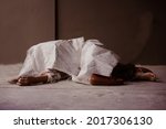 Small photo of Dead man lay down under white bag or cloth covered death body from accident or murder at house of victim. Covid-19 illness pass away person from low health care. Horror scene for Halloween.