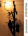 Small photo of The silhouette of power lineman climbing on an electric pole with a transformer installed. And replacing the damaged hotline clamp, bail clamp, dropout fuse cutout that causes a power outage.
