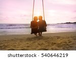 Romantic couple is sitting and kissing on sea beach on rope swing . Family vacation on honeymoon. Love and relationship