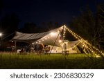 Small photo of Night camping scenes, long exposures in moving parts are blurry. Night camping with tent accommodation and relaxation seats, with an Asian family having dinner, playing guitar and having fun.