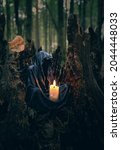 Small photo of mysterious black cloaked figure with burning candle in dark forest, abstract natural background. esoteric spiritual ritual for Samhain sabbat, Halloween. Magician, Grim Reaper, witchcraft ritual