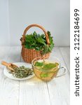 Small photo of Nettle tea in glass cup, fresh and dry nettle leaves on table close up. Urtica dioica, common stinging nettle, Ingredient for useful spring vitamin herbal tea. Traditional medicine, homeopathy concept