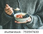 Healthy winter breakfast. Woman in woolen sweater eating rice coconut porridge with figs, berries, hazelnuts. Clean eating, vegetarian, vegan, alkiline diet food concept