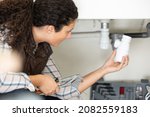 Small photo of woman tightening sink pipe with monkey wrench