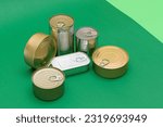 A Group of Stacked Tin Cans with Blank Edges on Green Background. Canned Food. Different Aluminum Cans for Safe and Long Term Storage of Food. Steel Sealed Food Storage Containers