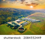 Small photo of Biogas plant and farm in green fields against sunset. Renewable energy from biomass. Aerial view to modern agriculture in Czech Republic and European Union.