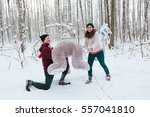 young handsome guy standing on his knee and does offer a pretty girl in winter forest