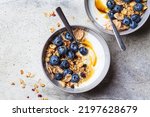 Breakfast yogurt bowl with granola, blueberries and maple syrup, gray background, top view, copy space. Healthy food concept.