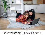 Small photo of Friendly relations of mom and her cute little daughter. They wallow at home on the floor in casual clothes and shopping online together using a laptop. They buy new toys for pretty little girl