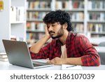 Small photo of Chronic sleep deprivation. Tired bored arabian or indian university student, is sleeping while sitting at desk in library, exhausted of learning, preparing for exam session, suffering of lack of