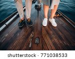 The legs of a guy and a girl in stylish shoes that stand on a wooden yacht floating on the sea