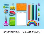 Small photo of Frame from school and office supplies Paper clips, pens, calculator, sharpener, notepad, stapler isolated on blue background Flat lay Top view Back to school, education concept Mock up Copy space