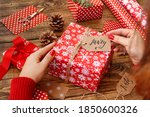 Woman wrapping a Christmas present on a wooden table close up