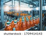 Small photo of Conveyor belt, juice in bottles, beverage factory interior in blue color, industrial production line.
